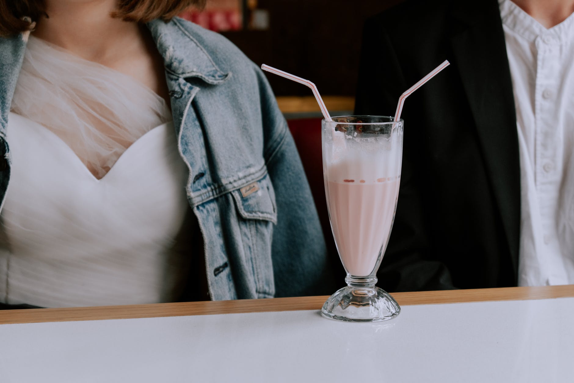 woman in white dress holding clear glass cup with pink liquid